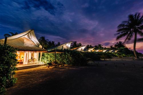 a row of resorts on the beach at night at Cinnamon Hakuraa Huraa Maldives - All Inclusive in Meemu Atoll
