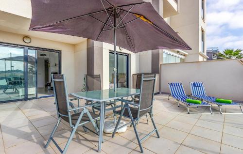 a table with chairs and an umbrella on a patio at 2 Bedroom Amazing Apartment In Orihuela in Orihuela