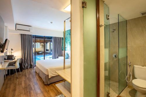 a bedroom with a bed and a bathroom with a shower at Liberta Seminyak Hotel in Seminyak