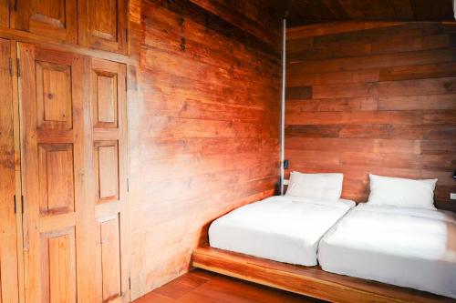 a bedroom with two beds in a wooden wall at Baan Inn in Chiang Dao