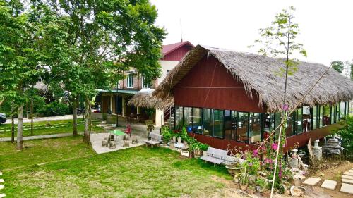 a building with a thatched roof and a yard at Cuc Phuong Bungalow in Phủ Nho Quan