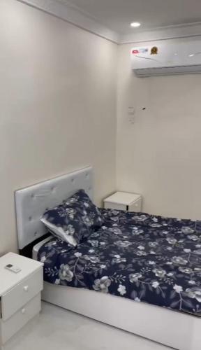 Schlafzimmer mit einem Bett mit einer blauen und weißen Bettdecke in der Unterkunft شقق لمى للايجار in Al Bad‘
