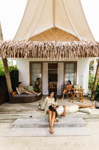 a group of people sitting on the porch of a tent at Cinnamon Hakuraa Huraa Maldives - All Inclusive in Meemu Atoll