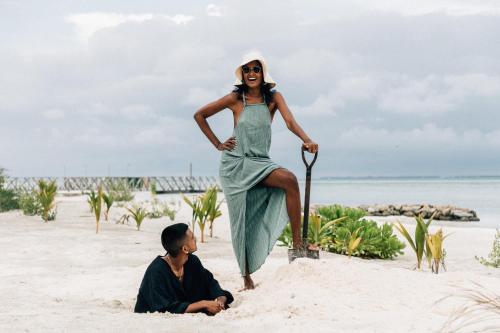 a woman in a dress standing on the beach at Cinnamon Hakuraa Huraa Maldives - All Inclusive in Meemu Atoll