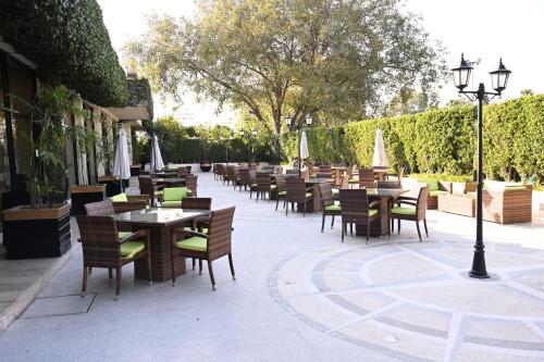 an outdoor restaurant with tables and chairs and umbrellas at Pearl Continental Hotel, Rawalpindi in Rawalpindi