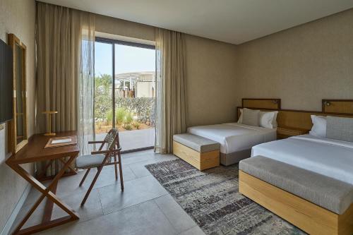 a hotel room with two beds and a desk and a window at ERTH Abu Dhabi Hotel in Abu Dhabi