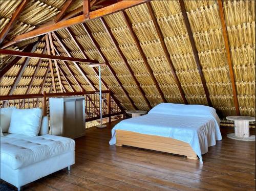 a bedroom with a bed and a couch in a straw roof at Amazing 5BR House with Ocean View in Cartagena in Playa Blanca