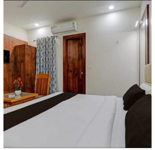 a bedroom with a white bed and a wooden door at PRAVI INN in Gomti Nagar