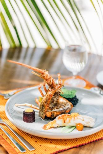 a plate of food with shrimp and vegetables on a table at Cinnamon Hakuraa Huraa Maldives - All Inclusive in Meemu Atoll