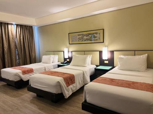 a hotel room with three beds in a room at Circle Inn - Iloilo City Center in Iloilo City