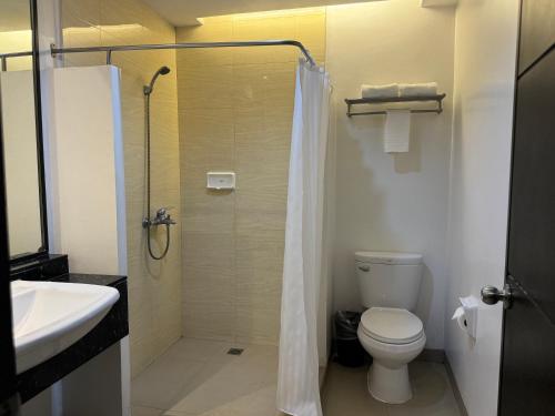 a bathroom with a shower and a toilet and a sink at Circle Inn - Iloilo City Center in Iloilo City