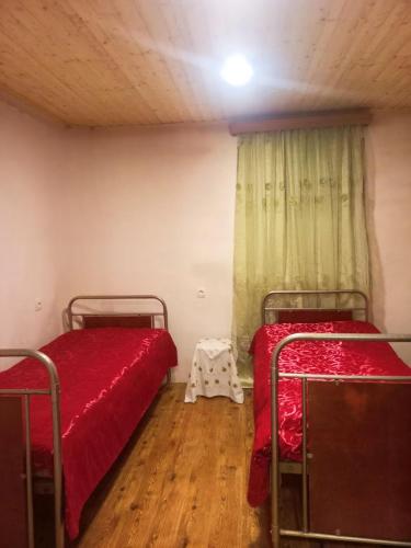 Habitación con 2 camas con sábanas rojas y mesa. en Hostel in Katskhi en Katsʼkhi