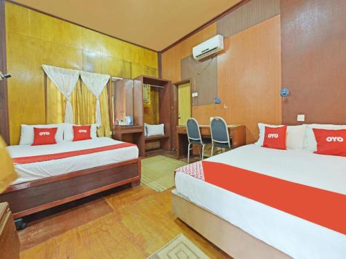 a bedroom with two beds and a desk and chairs at Pelangi Beach Resort in Cherating