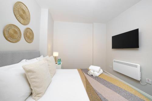 a bedroom with a white bed and a flat screen tv at Best Covent Garden/Chinatown/Soho Location in London