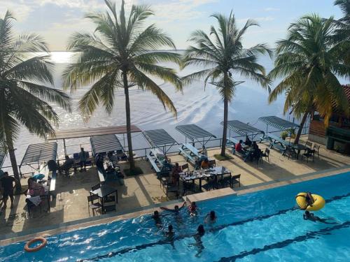 a view of a pool with palm trees and the ocean at New Saniro Lagoon Deck in Katunayake
