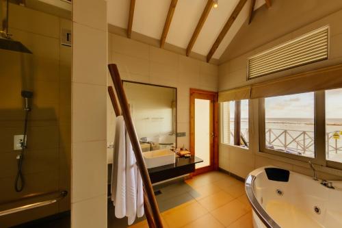 a bathroom with a tub and a sink and a window at Cinnamon Dhonveli Maldives in North Male Atoll