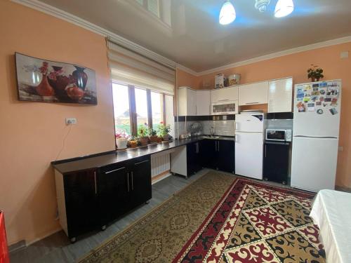 eine Küche mit weißen Geräten und einem großen Teppich in der Unterkunft Monchok Guest House in Naryn