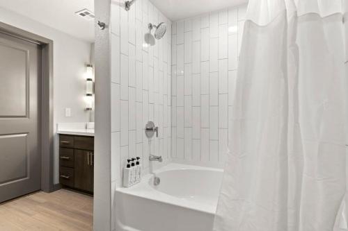 a white bathroom with a tub and a shower at Cozysuites PHX RORO Gym, Pool, Pets, Parking! #10 in Phoenix