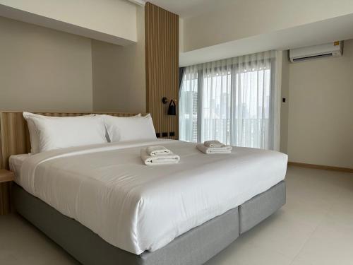 a large white bed in a room with a window at Jace hotel in Bangkok