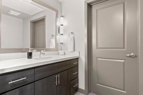 a bathroom with a sink and a mirror and a door at Cozysuites PHX RORO Gym, Pool, Pets, Parking! #11 in Phoenix