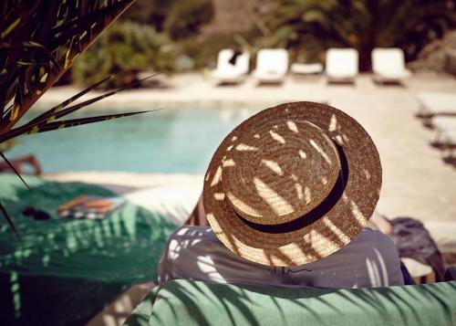 a person wearing a straw hat sitting next to a swimming pool at Azienda Agricola Mandranova in Palma di Montechiaro