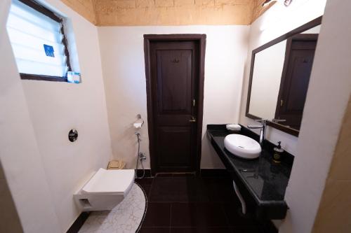 a bathroom with a toilet and a sink and a mirror at Tiger Trails Resort in Tāla