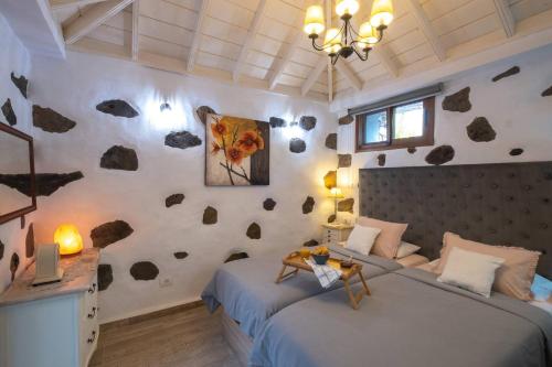 a bedroom with two beds and a wall with rocks at Casa Sophie by Huskalia - private pool in Los Llanos de Aridane