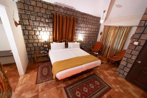 um quarto com uma cama e uma parede de tijolos em Tiger Trails Resort em Tāla