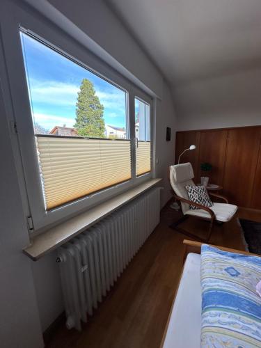 um quarto com uma grande janela com um radiador e uma cadeira em Ferienwohnung Burgunder-Paradies em Britzingen
