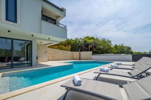een zwembad met ligstoelen naast een huis bij Pool Villa Greta Krk - Happy Rentals in Krk