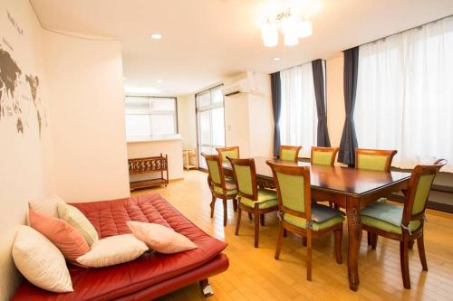 a dining room with a couch and a table and chairs at 那覇市内を満喫したいあなたへ！大人数宿泊可！国際通りまで徒歩4分！無料駐車場1台＆Wifi完備！ in Makishimachi