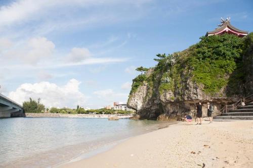 a group of people standing on a beach near the water at 那覇市内を満喫したいあなたへ！大人数宿泊可！国際通りまで徒歩4分！無料駐車場1台＆Wifi完備！ in Makishimachi