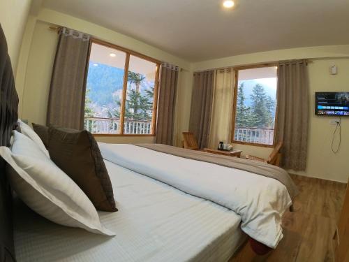 a bedroom with a large white bed with windows at Cloud 9 Chalet in Manāli