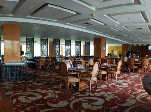 un comedor con mesas, sillas y ventanas en Five Premiere Hotel en Samarinda