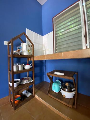 a kitchen with wooden shelves and a blue wall at Elephant bungalow at Ya Nui beach in Phuket
