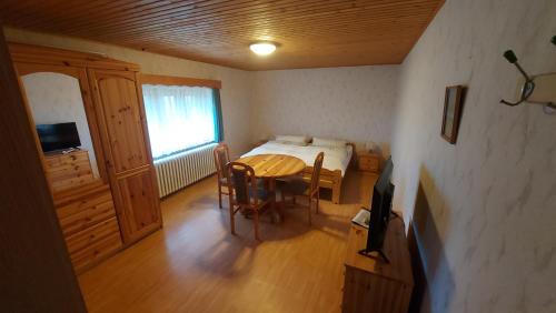 a bedroom with a bed and a table and chairs at Gästezimmer an der Loipe in Bienenmühle