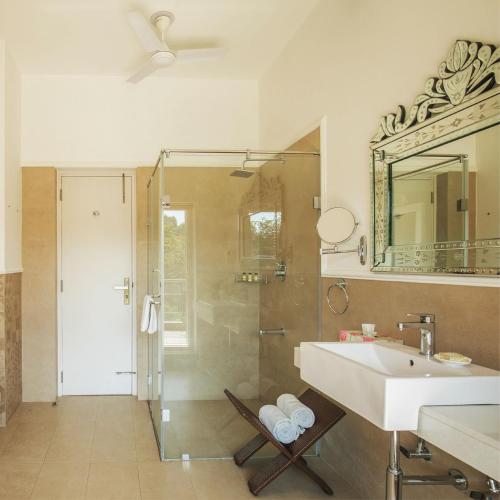 a bathroom with a shower and a sink and a mirror at Karma Chalets in Gurgaon