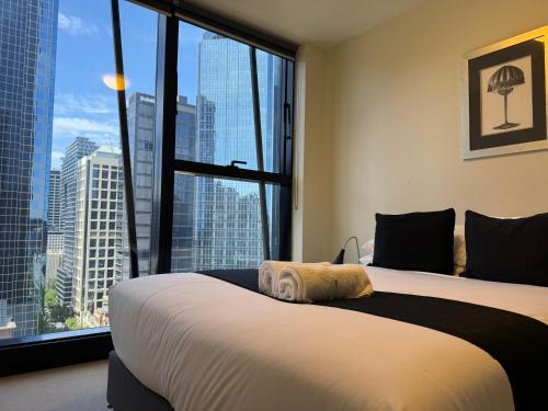 a bedroom with a large bed with a large window at Collins Serviced Apartments in Melbourne