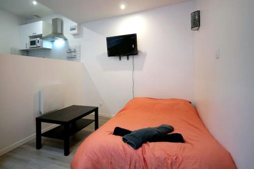a bedroom with a bed and a table and a television at L impérial 2 - Direct Gare- 35 mn Paris in Étampes