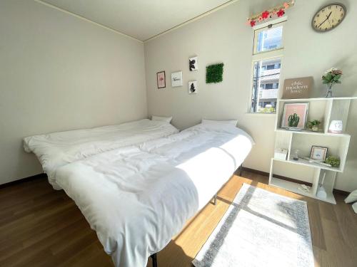een groot wit bed in een kamer met een klok bij Gest Residence EDORIVER Airport Line Self check in in Tokyo