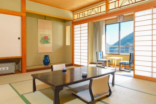 Cette chambre dispose d'une grande fenêtre et d'une table avec des chaises. dans l'établissement Ooedo Onsen Monogatari Kakeyu, à Ueda