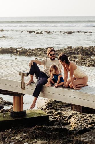 a family sitting on a dock on the beach at Cinnamon Dhonveli Maldives in North Male Atoll