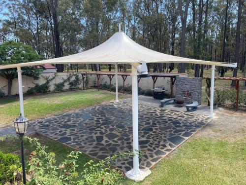 a white gazebo in a yard with a fireplace at Villa Provence in Pokolbin