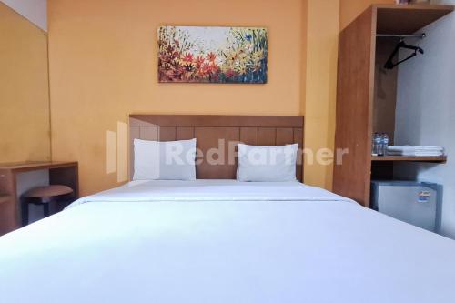 Un dormitorio con una cama blanca y un cuadro en la pared. en Nirvana Inn seturan Mitra RedDoorz, en Seturan