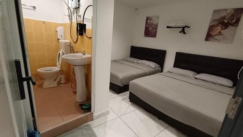 a small room with two beds and a sink and a bathroom at MUSANG ONG HOTEL in Cameron Highlands