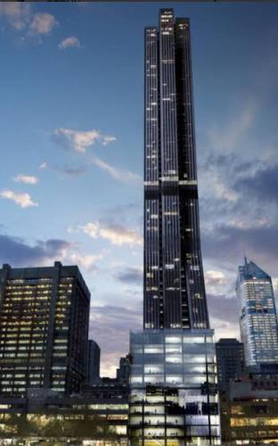 a tall skyscraper in front of a city skyline at Collins Serviced Apartments in Melbourne