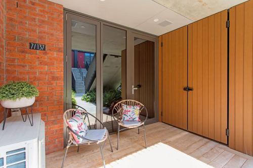 2 sillas sentadas en un patio con puertas de cristal en What A Cutie CBD 3 Mins to Handy Secure Park., en Christchurch