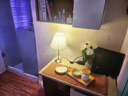 a desk with a lamp and a clock and a vase of flowers at The Stay Hill in Seoul