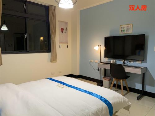 - une chambre avec un lit, un bureau et une télévision dans l'établissement 塔斯汀精品民宿, à Jinning