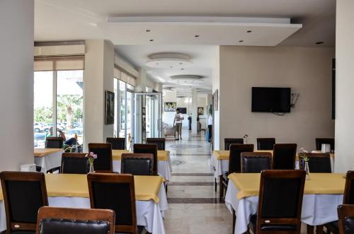 a dining room with tables and chairs and a tv at Perla Hotel in Dikili